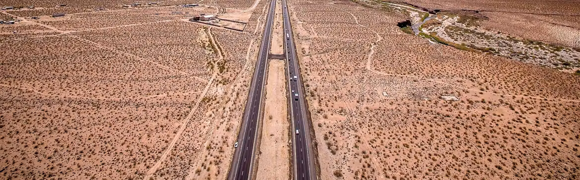 A two-lane highway running straight through open Arizona desert, seen from the air.